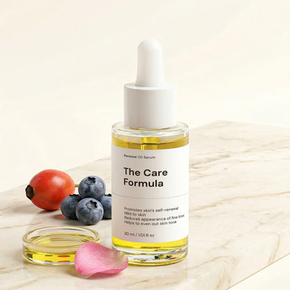 The Care Formula Renewal Oil Serum bottle dropper on a marble surface with fruits and petal