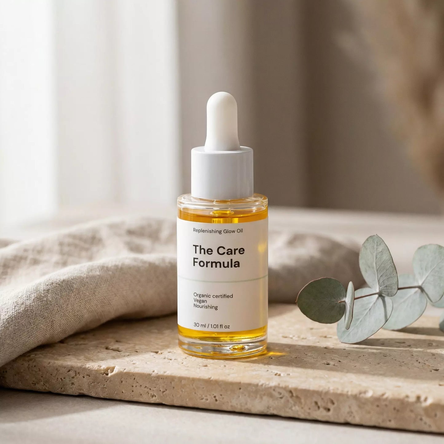The Care Formula Replenishing Glow Oil golden facial oil lifestyle scene on a neutral background with eucalyptus leaves.